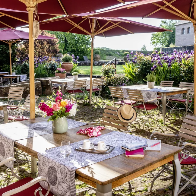 Sonnige Terrasse mit roten Sonnenschirmen, Tischen und Stühlen im Garten