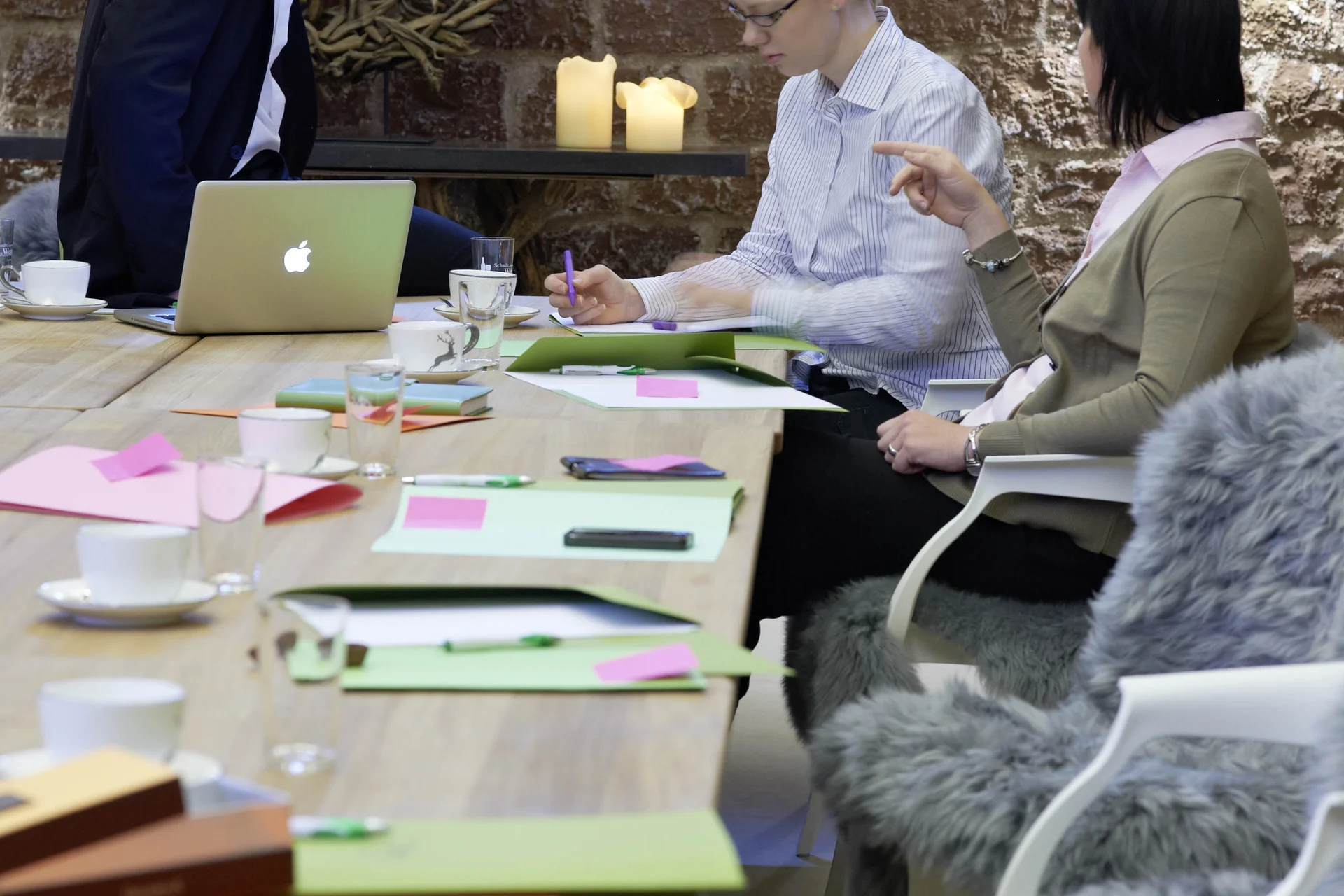 Drei Personen bei Besprechung an einem Tisch mit Laptop und Notizen