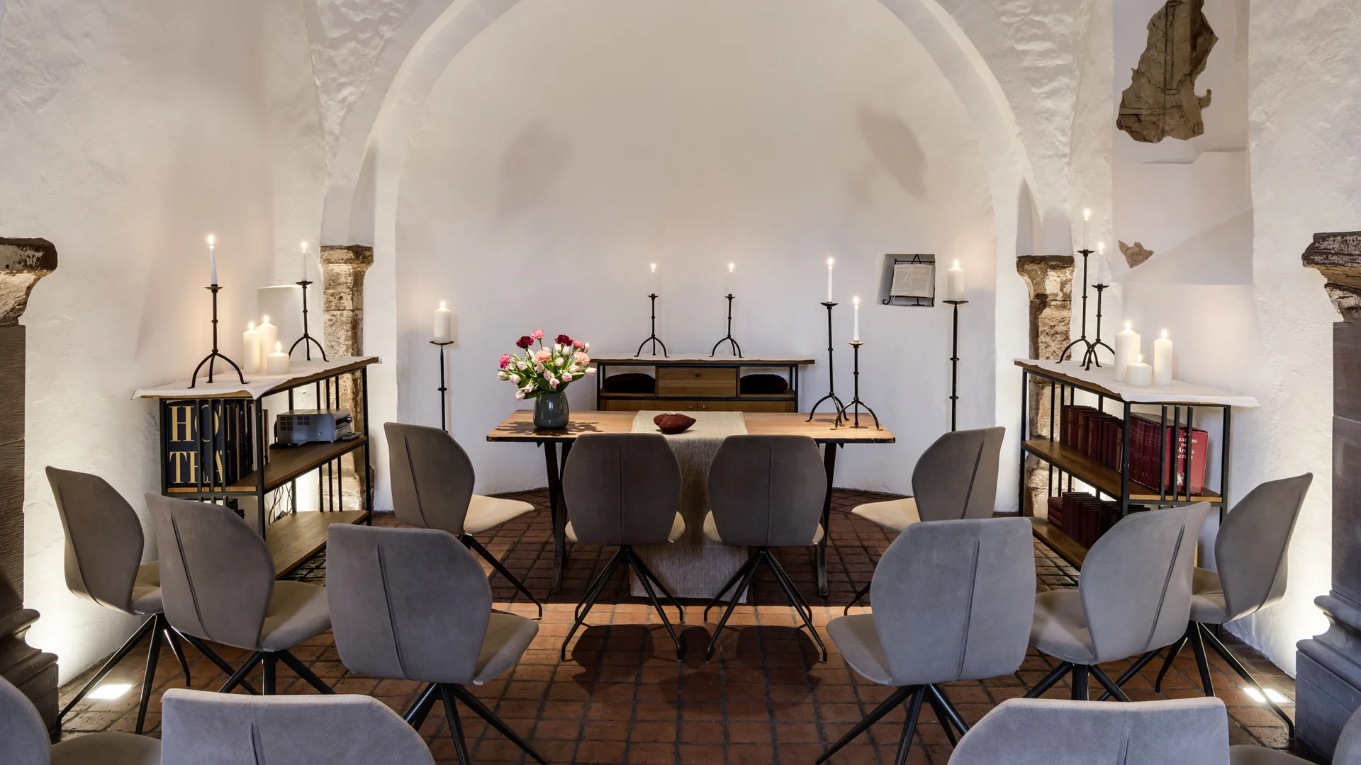 Kleiner, ruhiger Raum mit Stühlen, Kerzen und einem Tisch mit Blumen