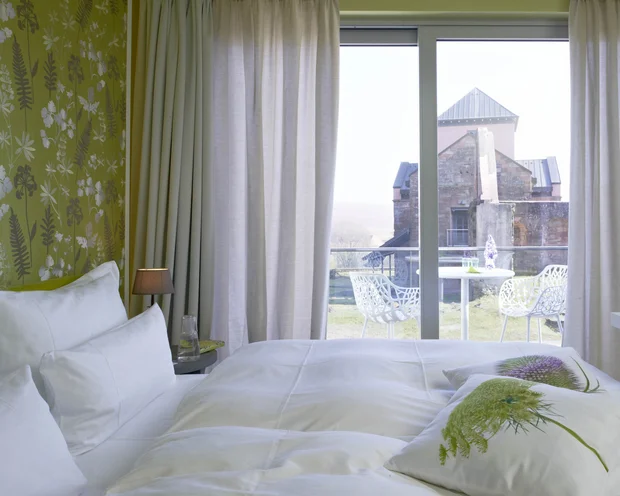 Hotelzimmer mit Balkon und Blick auf historische Burgmauer