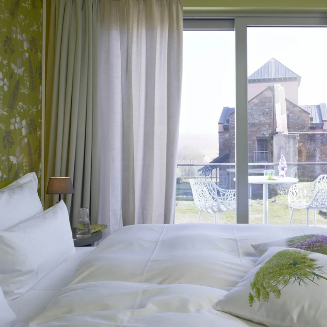 Hotelzimmer mit Balkon und Blick auf historische Burgmauer