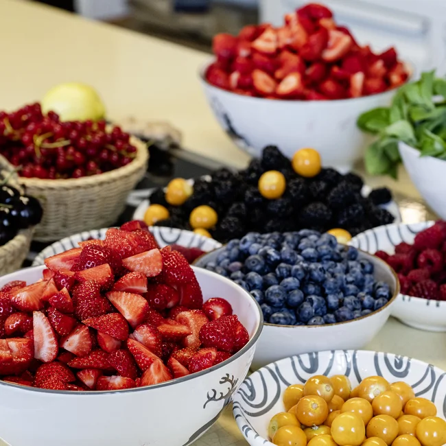 Verschiedene Beeren wie Erdbeeren, Himbeeren, Blaubeeren und Früchte in Schüsseln