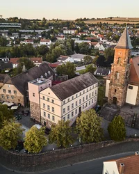 Luftaufnahme einer kleinen Stadt mit Kirche, alten Gebäuden und grünen Bäumen