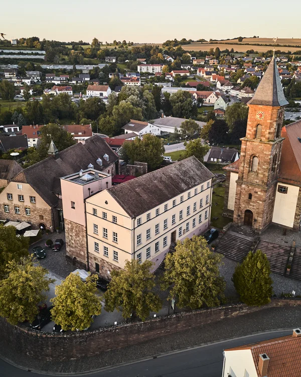 Luftaufnahme einer kleinen Stadt mit Kirche, alten Gebäuden und grünen Bäumen