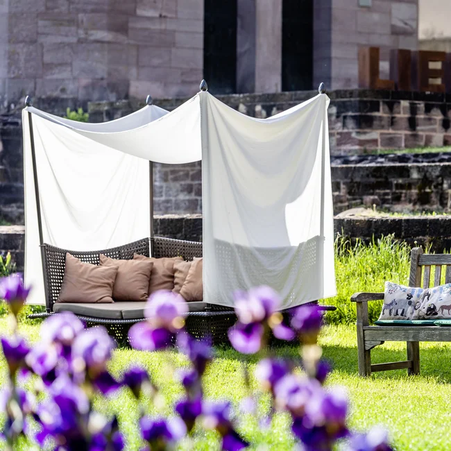 Gartenbereich mit Holzbank, gepolstertem Sitz und dem Schriftzug LIEBE im Hintergrund