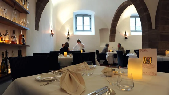 Elegantes Restaurant mit gedeckten Tischen und Gästen unter Bogenfenstern