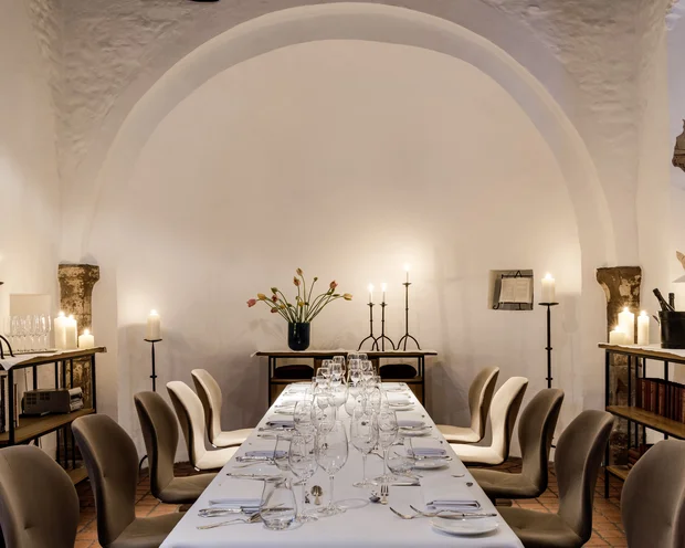 Eleganter Esstisch mit Kerzen in einem Raum mit weißem Bogen und Bücherregalen