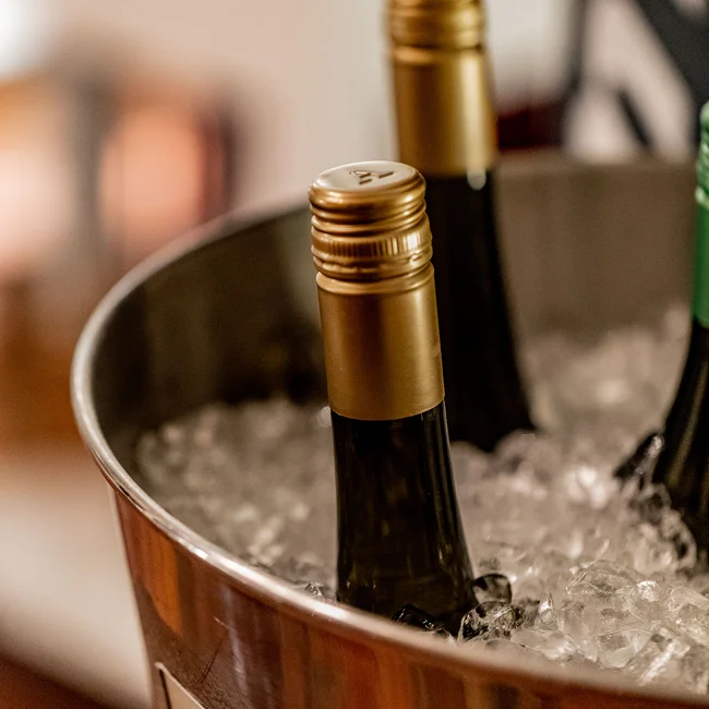 Weinflaschen mit goldenen Verschlüssen in einem Eisbehälter