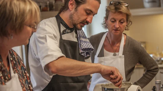 Koch erklärt zwei Frauen die Zubereitung mit Küchenmaschine in der Küche