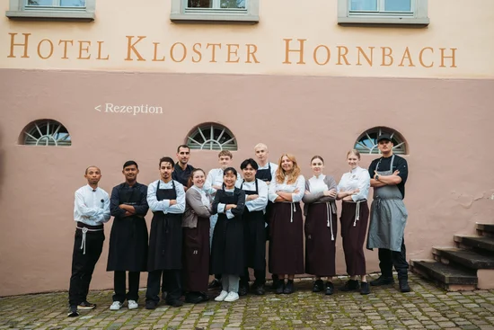 Abendbrot Hotel Kloster Hornbach Team steht vor dem Hotelfassade mit Empfangsschild