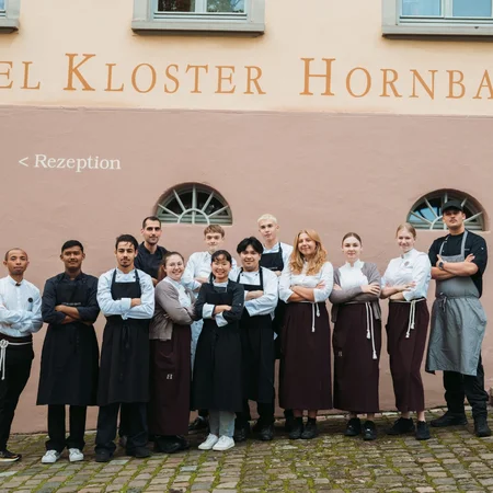 Hotel Kloster Hornbach Team steht vor dem Hotelfassade mit Empfangsschild