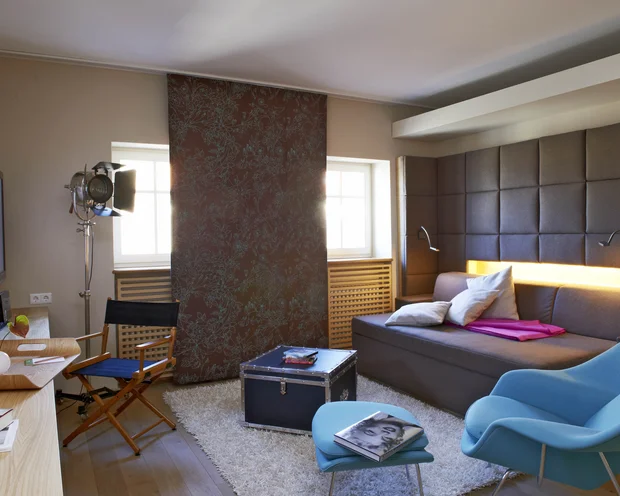 Gemütliches Wohnzimmer mit Sofa, blauem Sessel und Fernseher