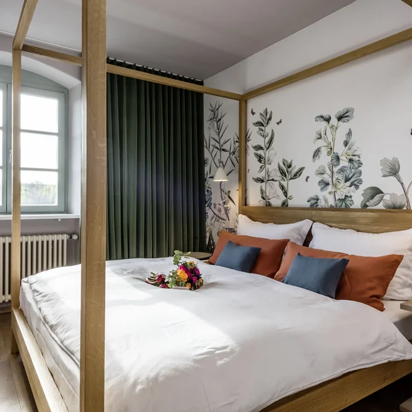 Hell eingerichtetes Schlafzimmer mit Himmelbett und floralem Wanddesign