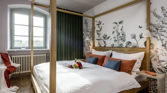 Hell eingerichtetes Schlafzimmer mit Himmelbett und floralem Wanddesign