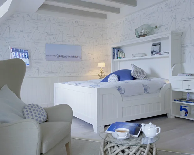 Helles Schlafzimmer mit weißem Bett, blau-weißem Dekor und maritimem Muster