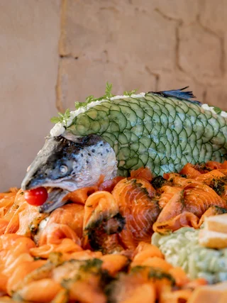 Lachsplatte mit rohem Lachs und dekoriertem Fischkopf mit Gurkenscheiben