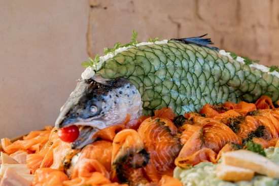 Lachsplatte mit rohem Lachs und dekoriertem Fischkopf mit Gurkenscheiben