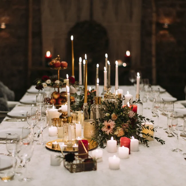 Eleganter gedeckter Tisch mit leuchtenden Kerzen und Blumenarrangements