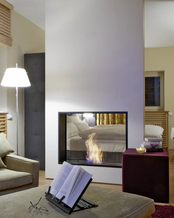 Modernes Wohnzimmer mit Kamin, Büchern und bequemen Sesseln bei Nacht