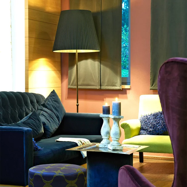 Gemütliches Wohnzimmer mit bunten Sesseln, Kerzen und Stehlampe