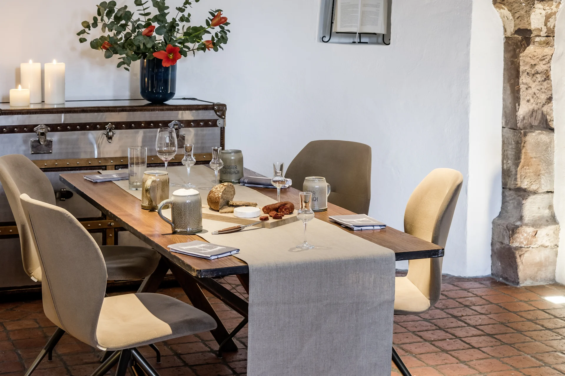Moderner Essbereich mit Holztisch, beigen Stühlen und Kerzen in einem Raum mit Rundbogen