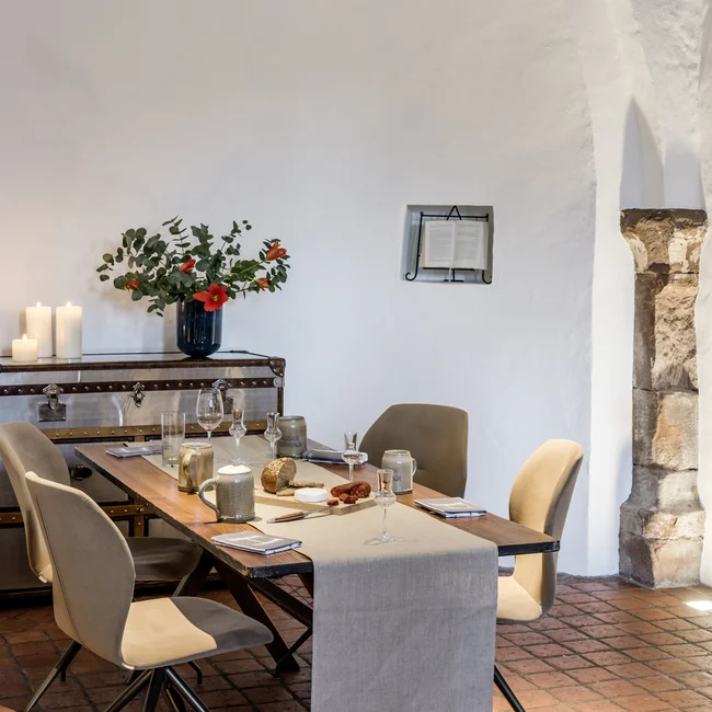 Moderner Essbereich mit Holztisch, beigen Stühlen und Kerzen in einem Raum mit Rundbogen