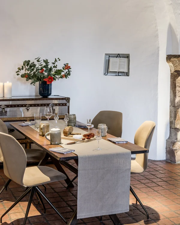 Moderner Essbereich mit Holztisch, beigen Stühlen und Kerzen in einem Raum mit Rundbogen