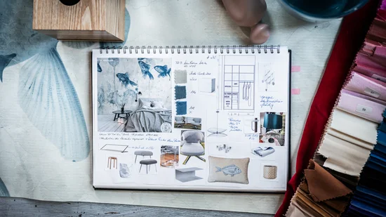 Aufgeschlagenes Moodboard mit Einrichtungsbildern und Farbmustern auf Tisch