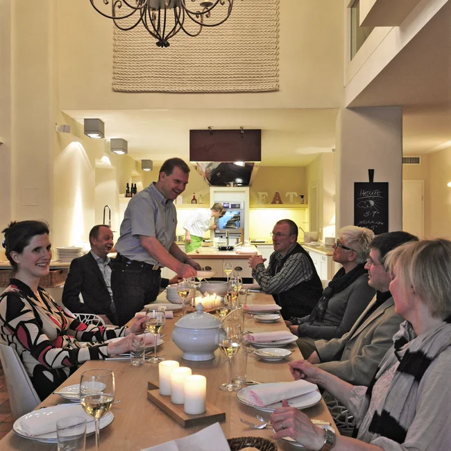 Gruppe von Menschen beim Abendessen an einem großen Tisch mit Kerzenbeleuchtung