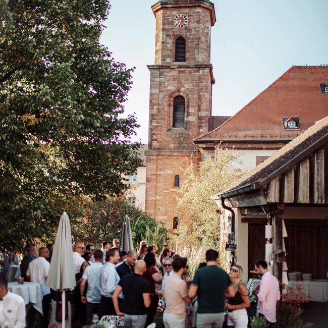 Menschen versammeln sich im Innenhof neben einem Kirchturm bei Tageslicht