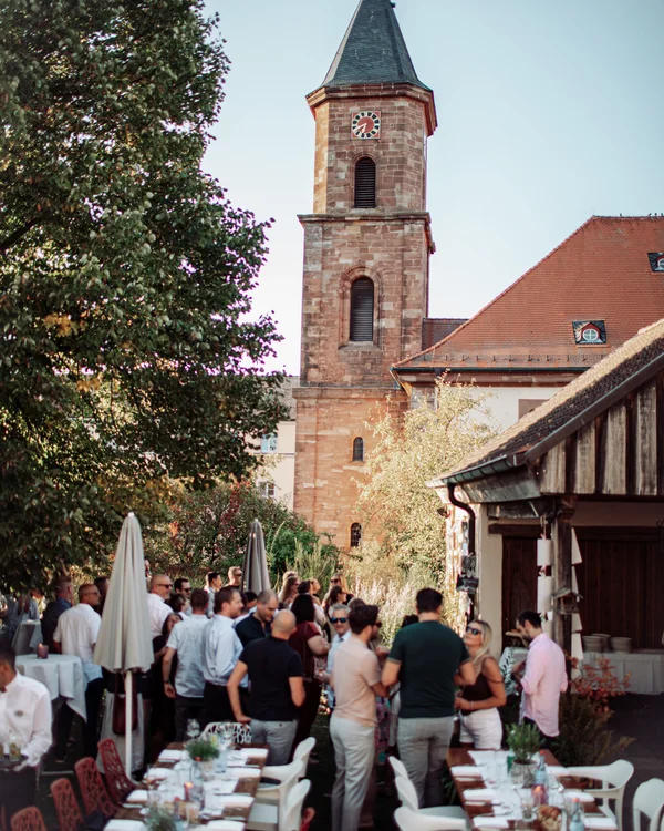 Menschen versammeln sich im Innenhof neben einem Kirchturm bei Tageslicht
