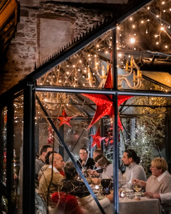 Menschen essen in einem festlich dekorierten Glashaus mit rot-leuchtenden Sternen