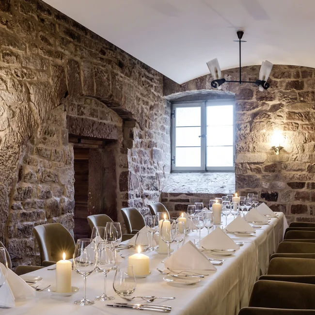 Eleganter Essraum mit Steinwänden und Kerzen auf einem gedeckten Tisch