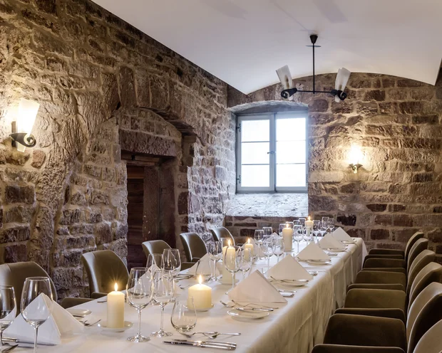 Eleganter Essraum mit Steinwänden und Kerzen auf einem gedeckten Tisch