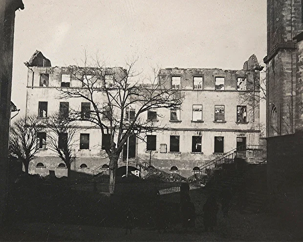 Zerstörtes Gebäude mit fehlendem Dach und kahlen Bäumen davor