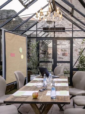 Konferenzraum im Gewächshaus mit Holztisch und beigen Stühlen