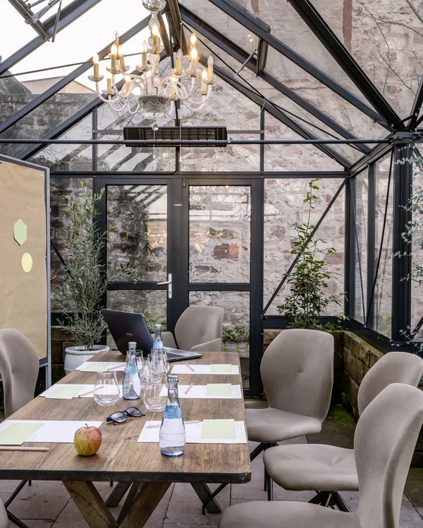 Konferenzraum im Gewächshaus mit Holztisch und beigen Stühlen