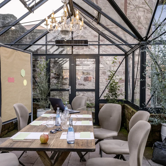 Konferenzraum im Gewächshaus mit Holztisch und beigen Stühlen