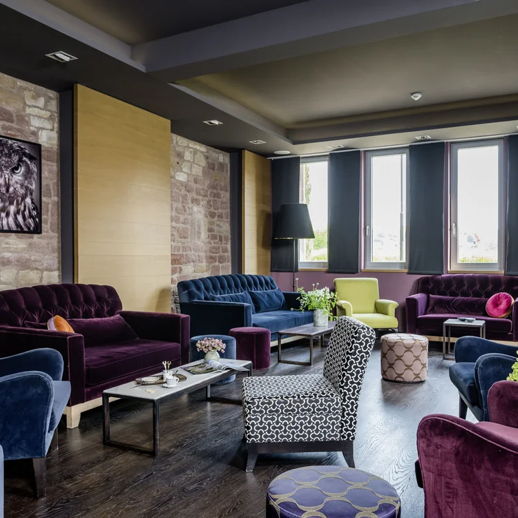 Gemütlicher Lounge-Bereich mit farbigen Sesseln, Sofas und Hockern in modernem Stil