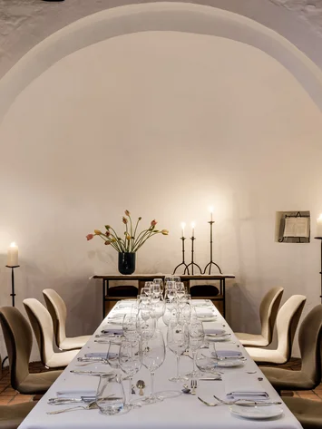 Eleganter Esstisch in einem historischen Raum mit Kerzen und Blumen dekoriert