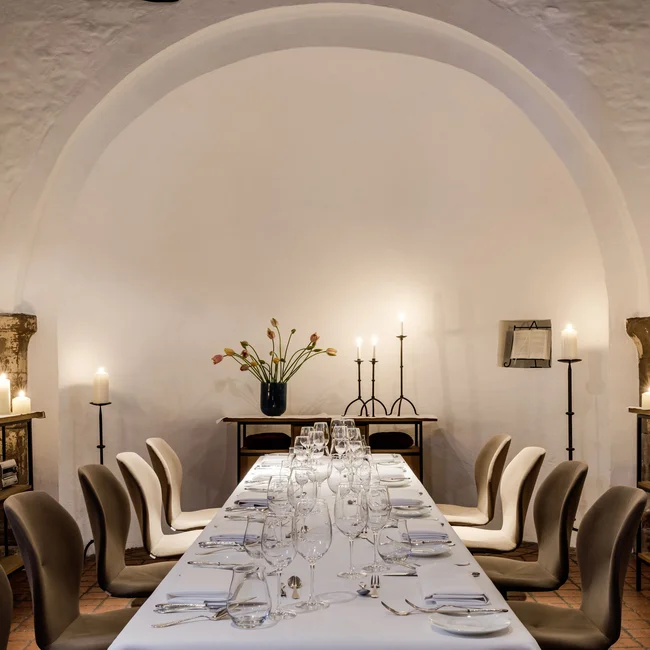 Eleganter Esstisch in einem historischen Raum mit Kerzen und Blumen dekoriert