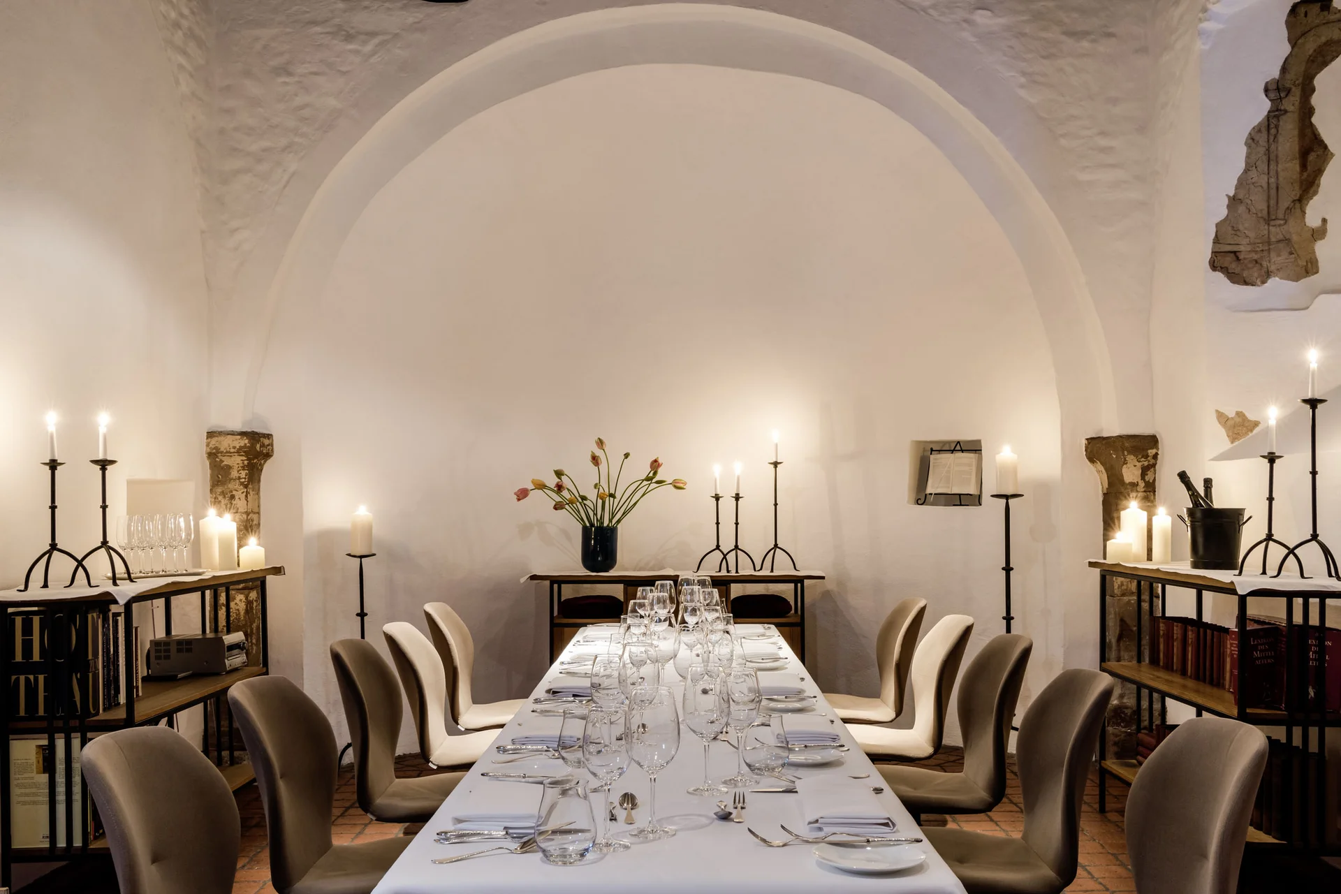 Eleganter Esstisch in einem historischen Raum mit Kerzen und Blumen dekoriert