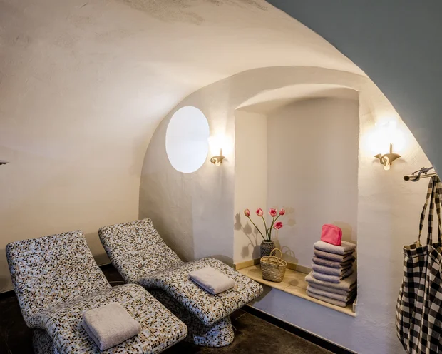 Ruhezone mit zwei Liegestühlen, Handtüchern und Blumen in einem weißen Raum