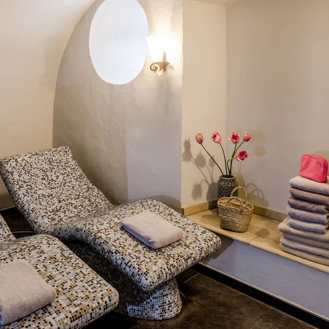 Ruhezone mit zwei Liegestühlen, Handtüchern und Blumen in einem weißen Raum