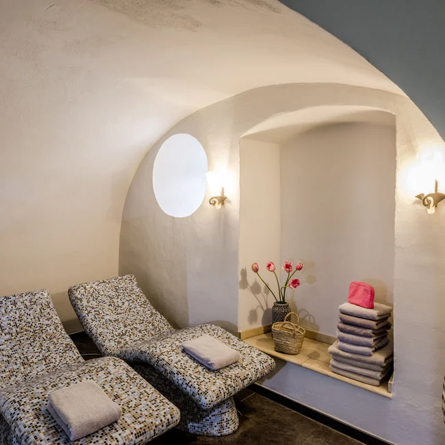 Ruhezone mit zwei Liegestühlen, Handtüchern und Blumen in einem weißen Raum