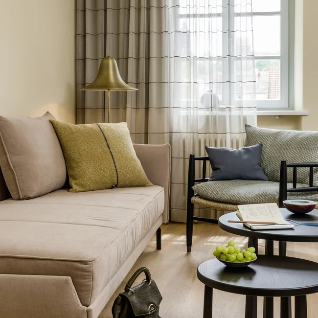 Gemütliches Wohnzimmer mit beigem Sofa, Sessel und schwarzen Couchtischen