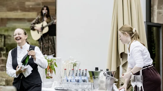 Zwei Kellnerinnen bereiten Getränke und Gläser bei einer Veranstaltung vor