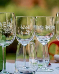 Mehrere Weingläser mit Aufdrucken stehen auf einem Tisch im Freien