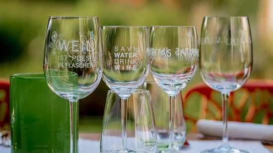 Mehrere Weingläser mit Aufdrucken stehen auf einem Tisch im Freien