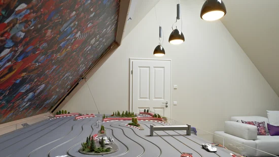 Modell-Rennbahn mit kleinen Autos in einem modernen Raum mit Sofa und Lampen